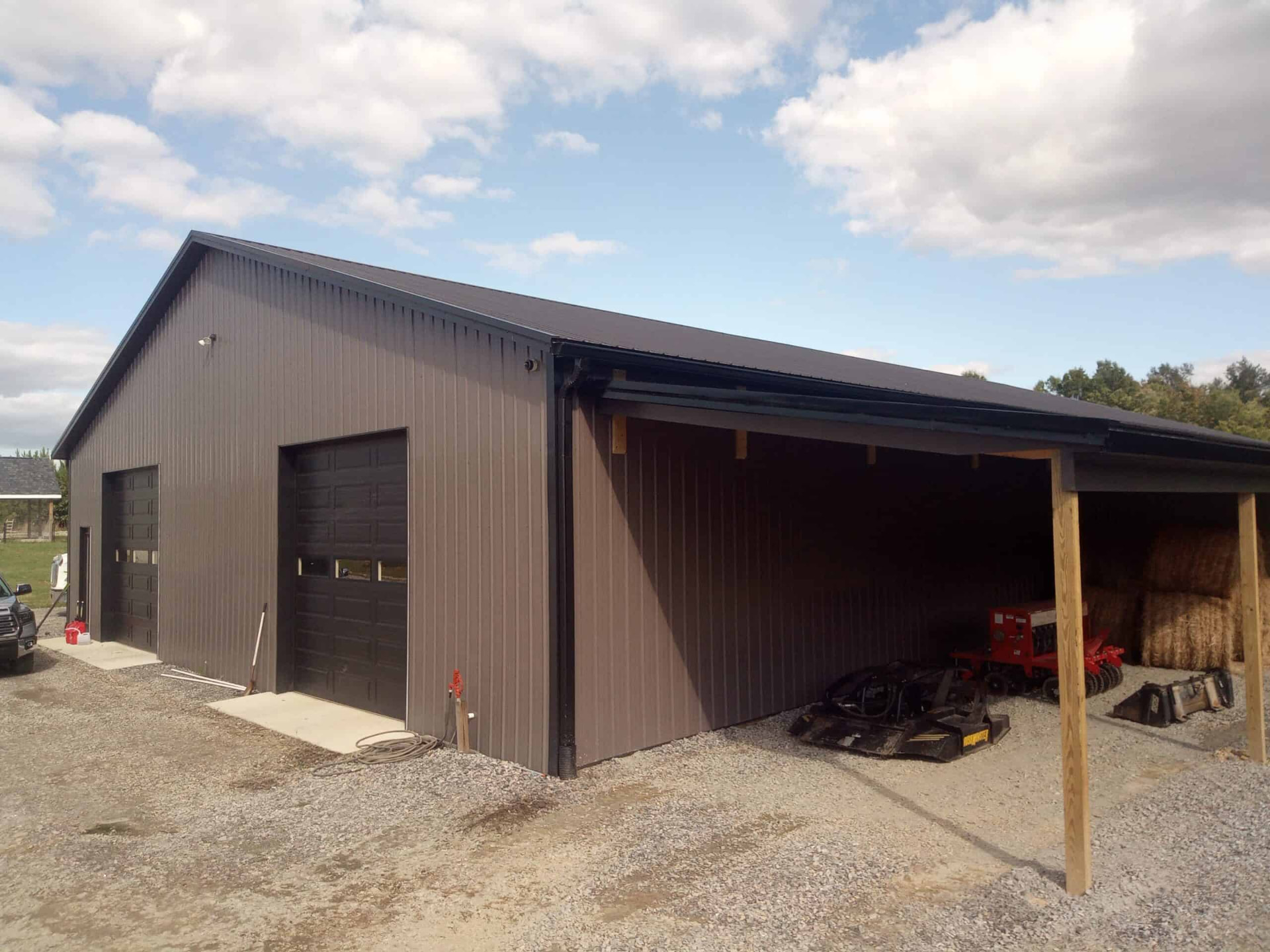 Large dark metal equipment barn with covered storage